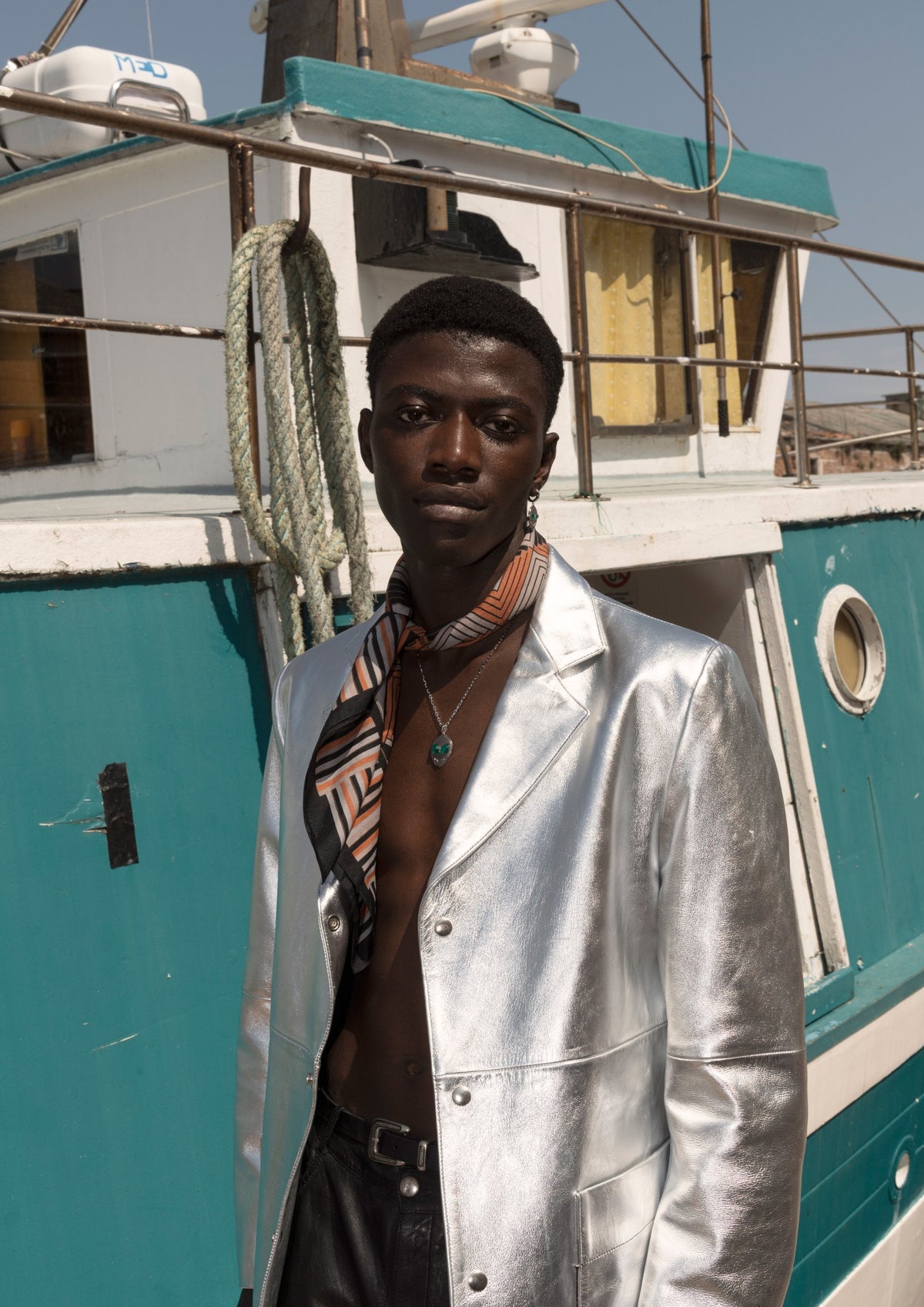 DARKAI Raw Energy Lookbook SS22 Man in urban landscape with gold alien pendant