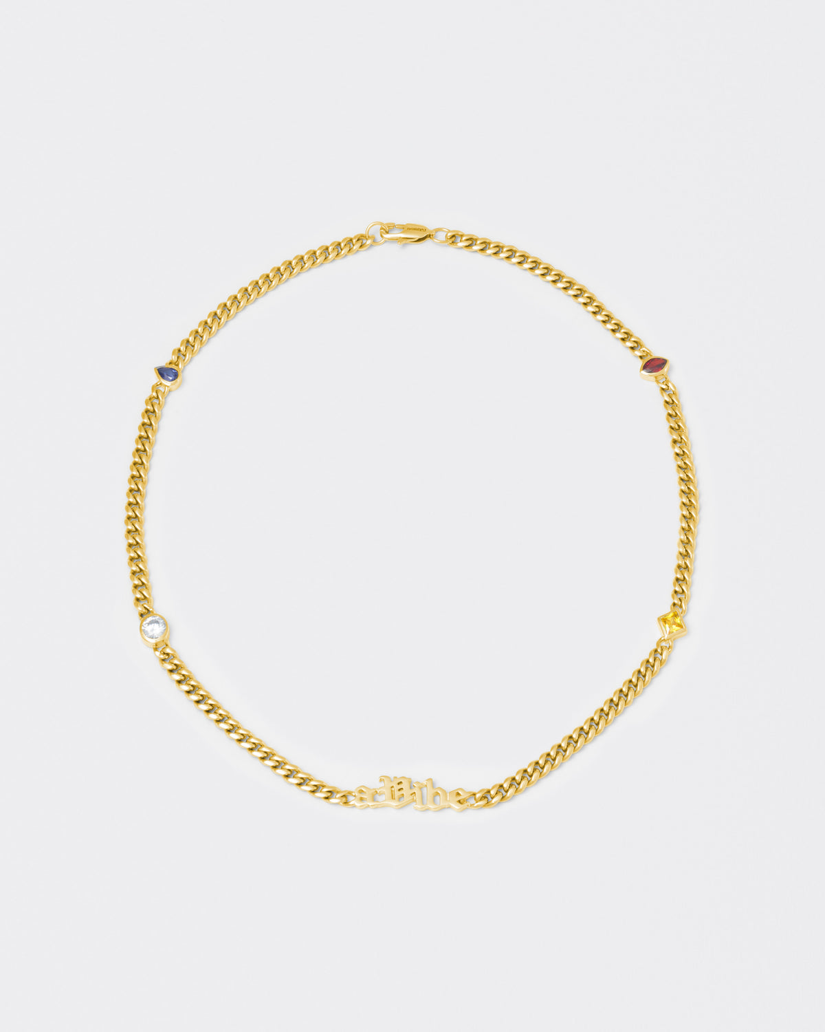 A Vibe cuban chain necklace with 18kt yellow gold coating, mixed shape bezel stones in diamond white, yellow, garnet, tanzanite and "A Vibe" central metal tag. Lobster clasp with logo