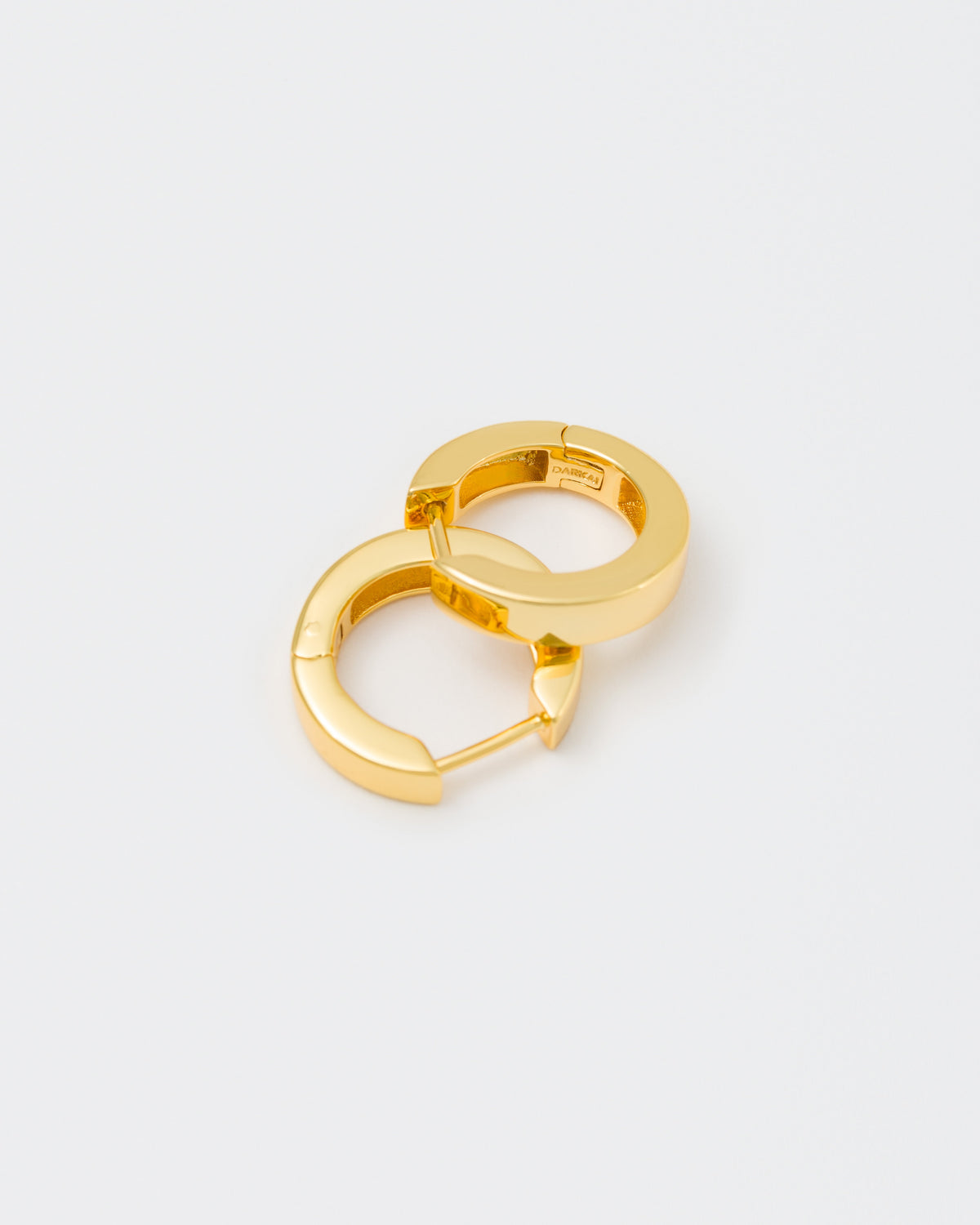 detail of 18k yellow gold coated hoop earrings with lasered logo and details on the inside